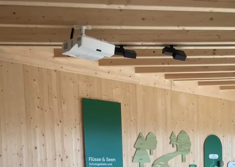 Fest installierter Deckenprojektor und Lautsprecher an einer Holzdecke